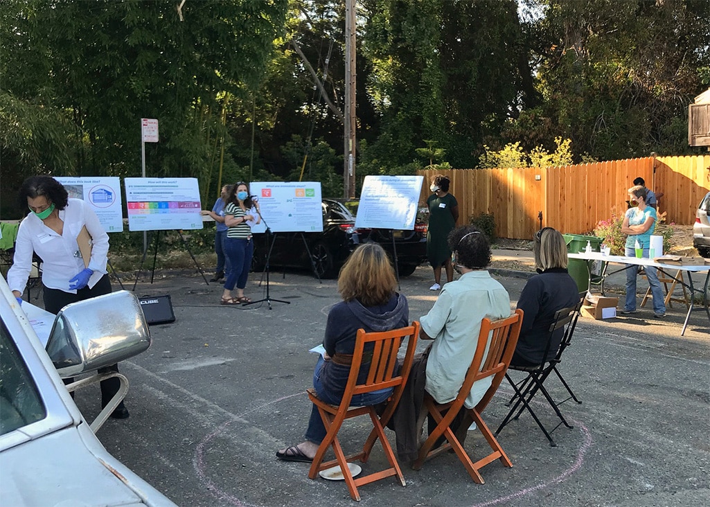 The EcoBlock research team stands in front of poster boards and shares project updates with neighborhood block residents