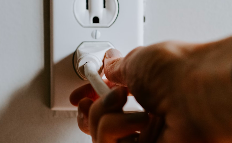 A person holding a plug to an outlet