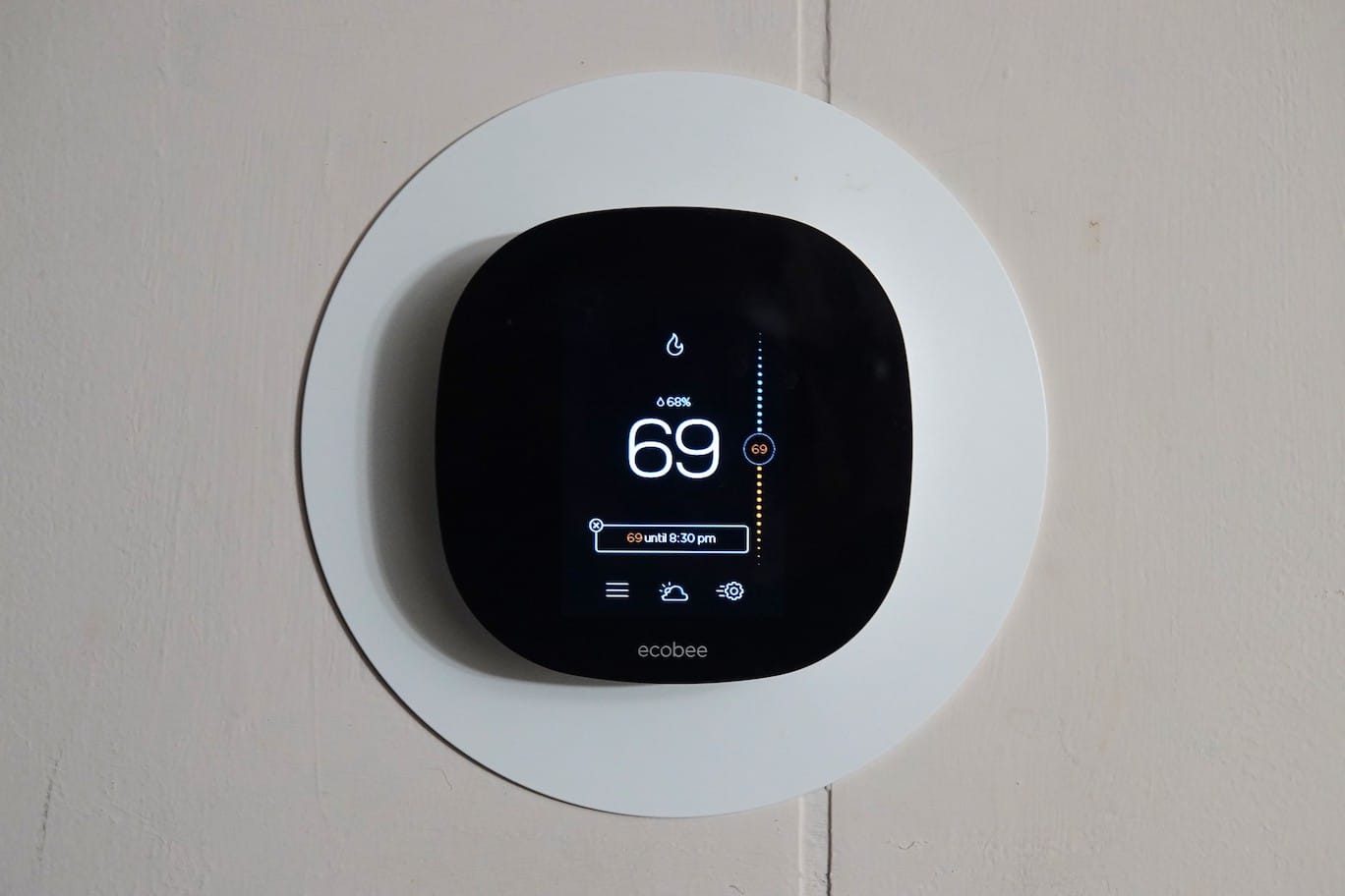 A square-shaped smart thermostat depicting a home’s indoor temperature.