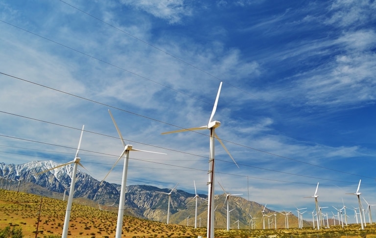 Wind turbines in Palm Springs, California. Mountain and blue sky in the background.