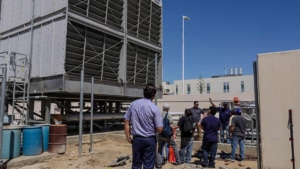 Students gathered around a large outdoor industrial cooling tower on the Bakersfield College campus